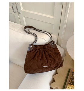 Close-up of dark brown suede bucket bag with quilted patterns and silver chain strap