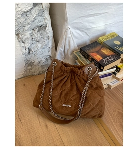 Detail view of brown suede bucket bag with diamond stitching and silver chain strap