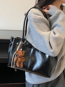 Retro black matte tote bag with teddy bear charm shown as a shoulder bag on model