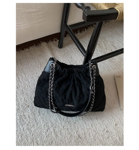 Detailed view of black quilted faux suede bucket bag with silver chain strap and logo