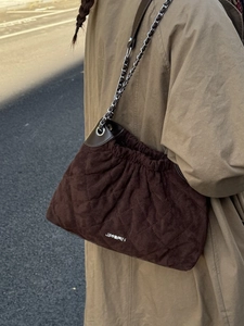 Quilted brown suede bucket bag with elegant silver chain strap and metal logo detail