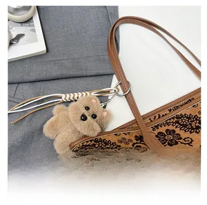 Close-up of vintage paisley tote bag with a cute plush bear pendant and leather handle