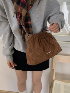 Quilted brown velvet bucket bag with silver chain strap shown on model's shoulder