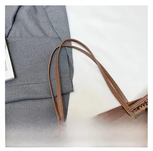 Detail of reinforced brown leather handles with fine stitching on a vintage printed tote