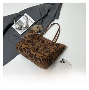 Detail of vintage paisley tote bag with brown leather straps and cute bear pendant charm