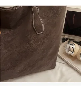 Gros plan du sac cabas marron à texture galet avec coutures blanches et accessoires