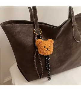 Gros plan d'un bijou de sac ours en peluche avec cordons tressés et anneau doré sur sac