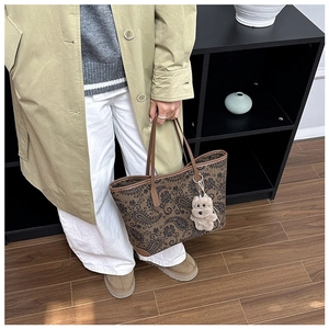 Detailed view of retro paisley print tote bag with brown handles and plush bear charm