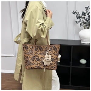 Detailed view of large paisley print tote bag in brown with plush puppy charm on model