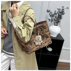 Detail of vintage paisley print tote bag with plush bear charm and long shoulder straps