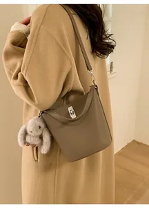 Détail du sac seau en cuir taupe avec fermoir rotatif argenté et breloque lapin