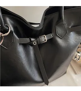 Detail of glossy black leather tote bag with polished silver buckles and metallic hardware