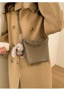 Détail du sac seau en cuir gris éléphant avec fermoir pivotant et breloque lapin en peluche