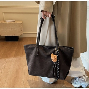 Détail du sac cabas en daim marron foncé avec surpiqûres blanches et charme d'ours