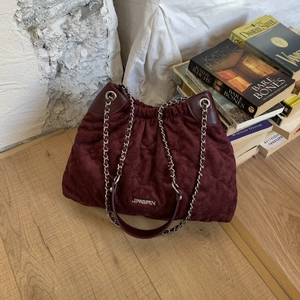 Macro detail of the wine red quilted velvet bucket bag with silver chain handle