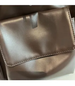 Macro shot of dark brown soft leather tote bag showing fine stitching and smooth texture