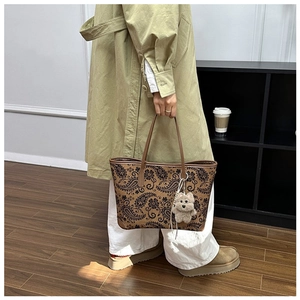 Detail of vintage paisley tote bag with plush puppy pendant shown on shoulder