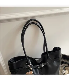 Close-up of black leather tote bag with sturdy handles and a plush charm detail