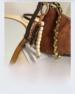 Detail of brown suede tote with vintage wooden bead tassel and gold chain strap