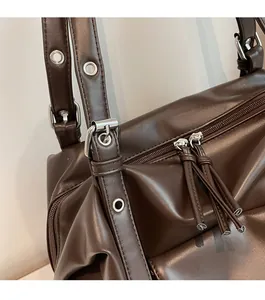 Detailed shot of dark brown glossy leather with silver eyelets and tassel zipper detail