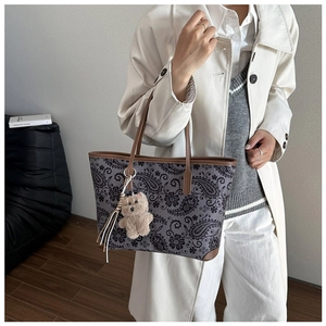 Detail of vintage paisley tote bag with brown leather trim and cute bear charm