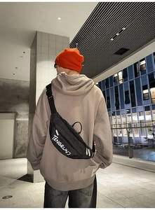 Streetstyle weergave van geruite crossbodytas met wit logo en reflecterende elementen