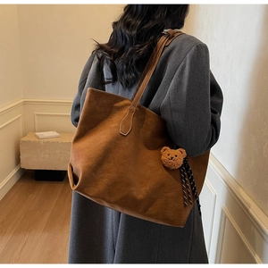 Détail d'un grand sac cabas en daim marron avec un joli pendentif ours en peluche doux