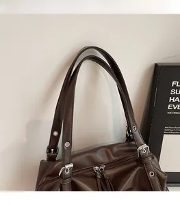 Close-up of vintage brown tote bag with matte leather texture and silver zipper hardware
