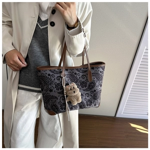 Detailed view of vintage paisley print tote bag with brown leather handles and plush dog charm