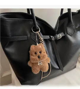 Brown fluffy plush charm with pearl necklace and Top Dog tag on a black tote bag