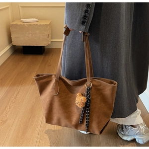 Détail du grand cabas en cuir mat marron avec breloque ours et pompon tissé élégant
