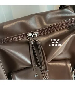 Close-up of smooth metal zippers with leather pulls on a vintage brown tote bag