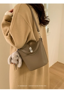 Détail du sac seau en cuir gris-brun avec fermoir argenté et pompon en peluche