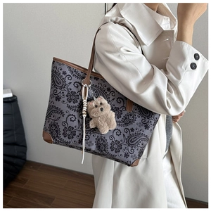 Detail of vintage paisley tote bag with brown leather trim and cute bear charm