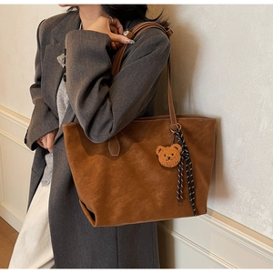 Détail du sac cabas en daim marron avec breloque ours en peluche et ruban rayé chic