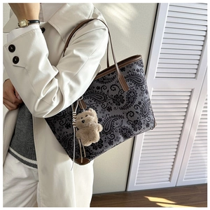 Detail of vintage paisley tote bag with brown leather straps and plush bear charm
