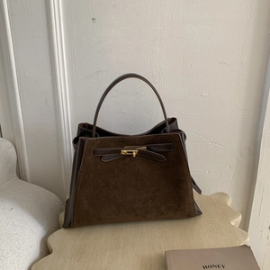 Detailed close-up of brown patchwork bucket bag featuring golden buckle and suede textures