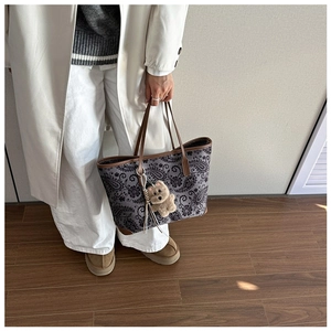 Detail of vintage paisley tote bag with leather trim and brown teddy bear charm