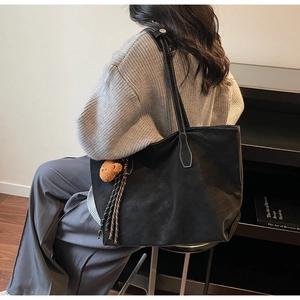 Détail du grand sac cabas noir en daim avec surpiqûres blanches et pendentif d'ours