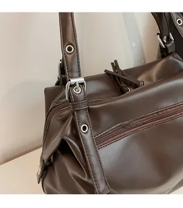 Detail of adjustable shoulder strap with silver metal buckle on a brown leather tote bag