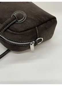 Dettaglio della borsa in pelle opaca marrone scuro con cuciture bianche e logo
