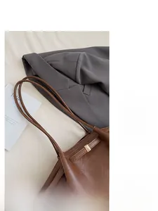 Détails d'un sac cabas en cuir marron avec boucles en métal doré et fines doubles bretelles