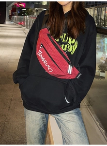 Streetstyle-weergave van een rode geruite crossbodytas met logo en verstelbare riem