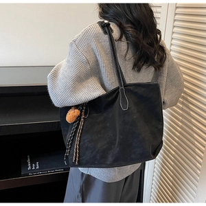 Détail du grand sac cabas en cuir mat noir avec coutures contrastées et charme d'ours