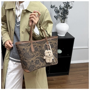 Detail of vintage paisley tote bag with leather handle and cute plush bear charm decoration
