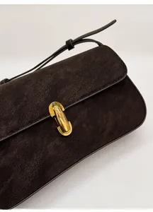 Détail du sac en daim vintage avec un fermoir rotatif ovale doré sur le rabat