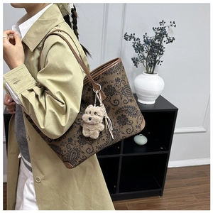 Detailed view of vintage floral tote bag with leather straps and plush puppy charm