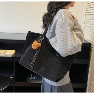 Détail d'un grand sac cabas noir avec pendentif ours marron et cordon décoratif rayé