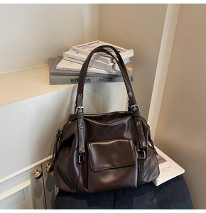 Detail of dark brown tote bag with front flap pocket and polished silver hardware