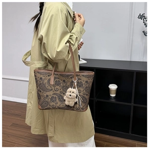Detail of vintage paisley tote bag with plush bear charm worn on the shoulder
